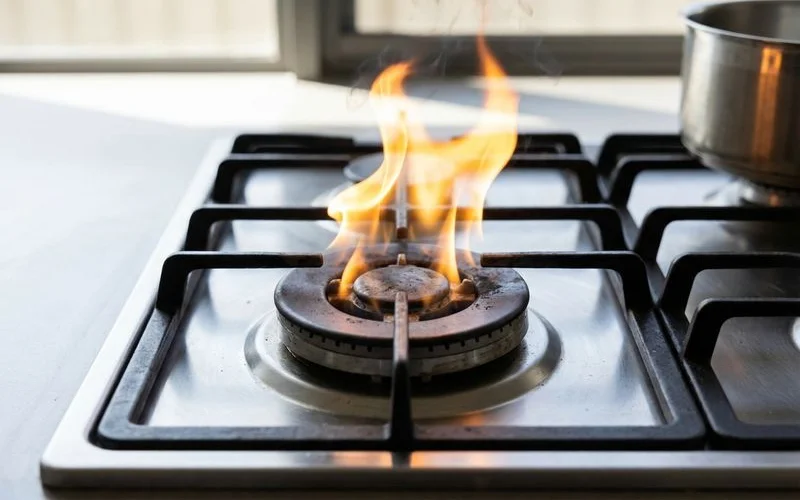 Gas stove burner with yellow flame instead of blue indicating potential gas supply issue or combustion problem at home
